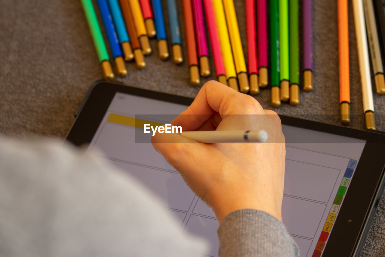 Cropped hand of woman using digital tablet on table