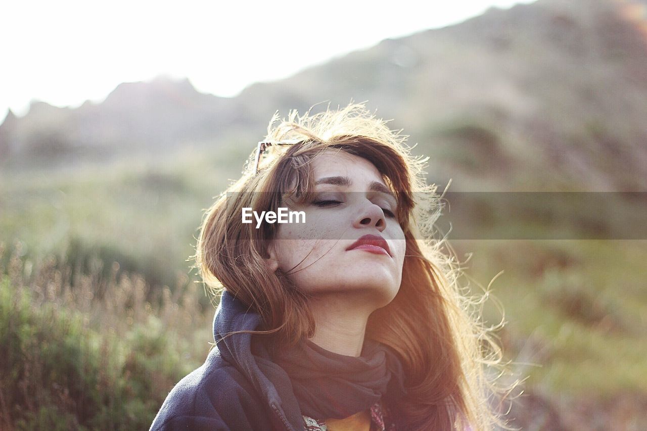 Close-up of woman with closed eyes against mountains