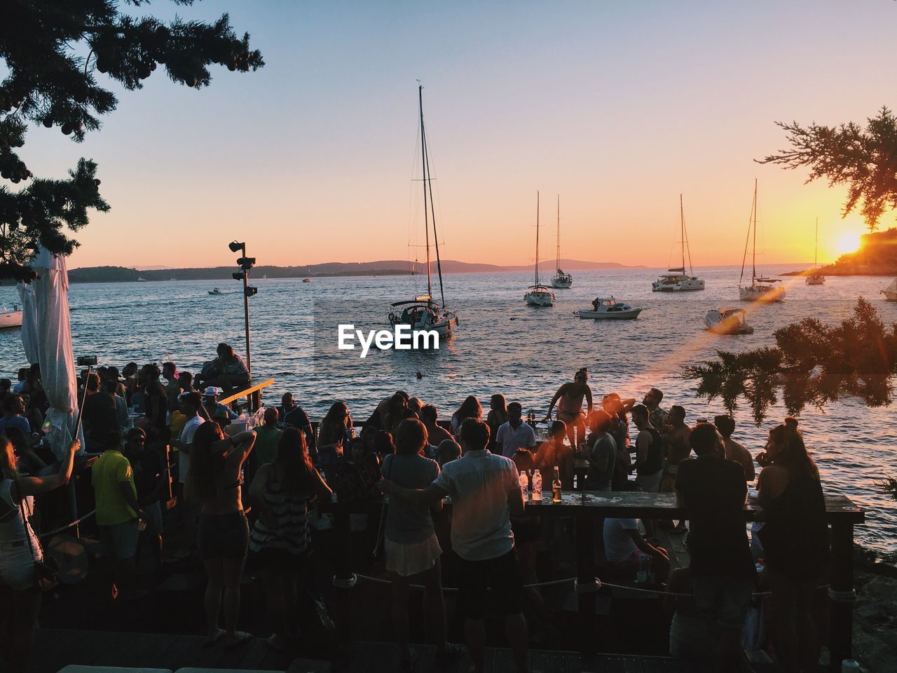 People enjoying at beach during sunset