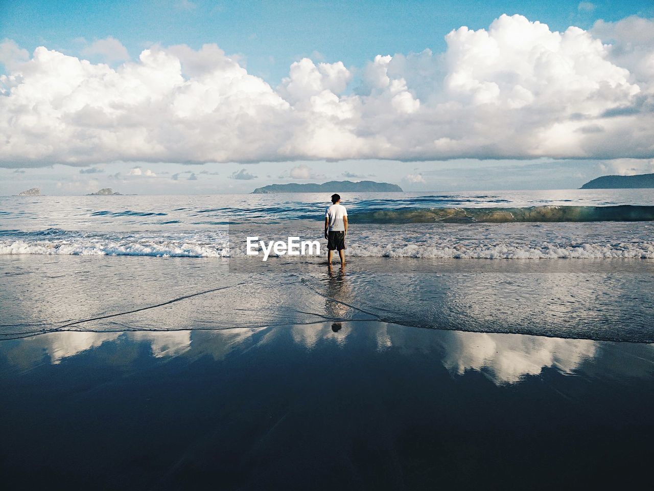 REAR VIEW OF PERSON STANDING ON BEACH