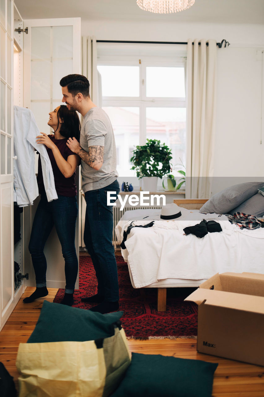 Man and woman arranging clothes together in closet at new home