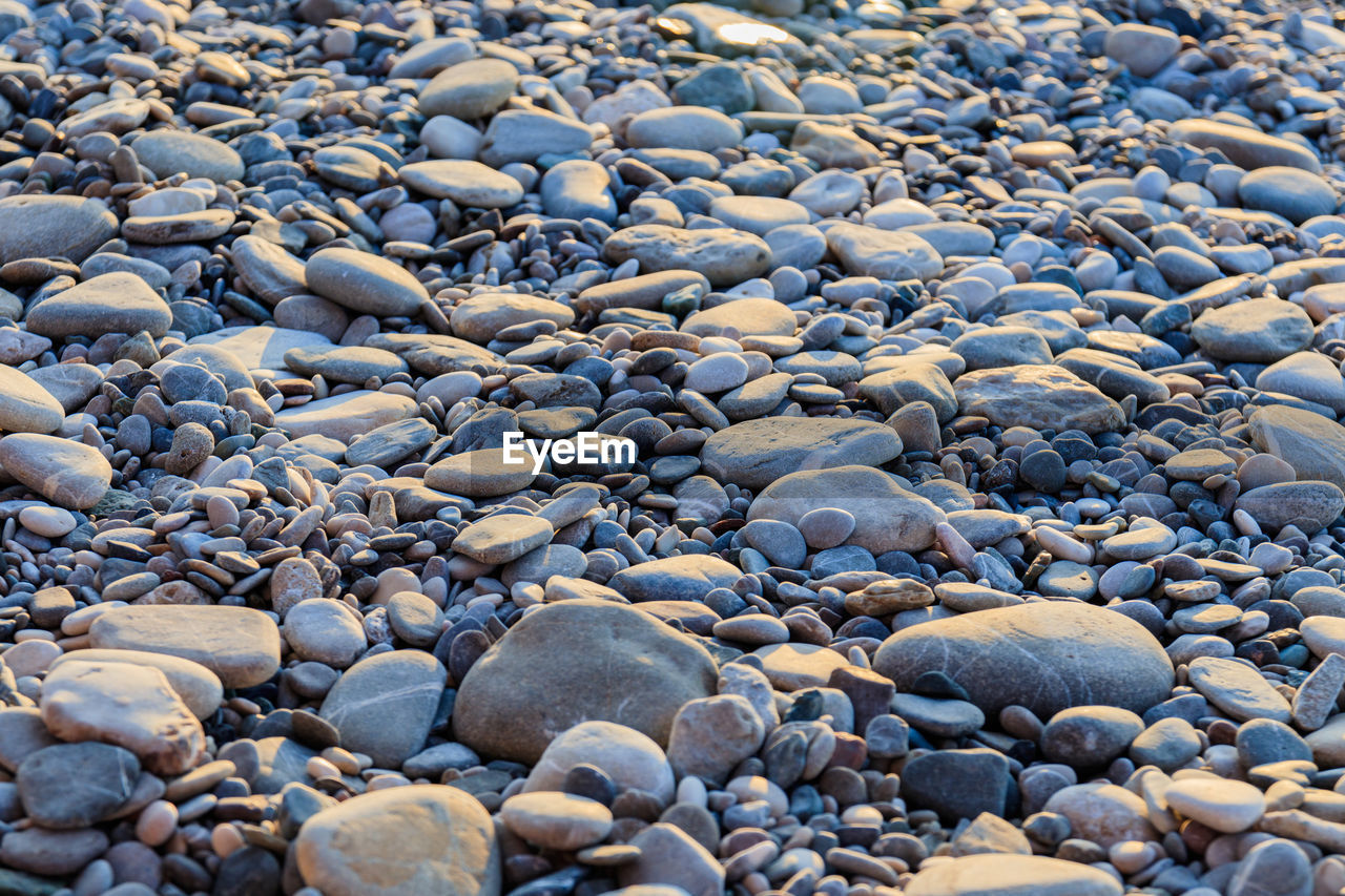 HIGH ANGLE VIEW OF PEBBLES ON BEACH