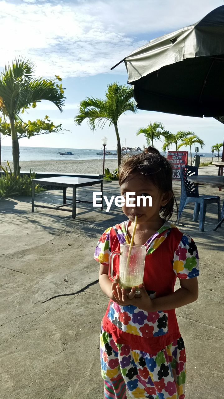 Portrait of girl having drink at beach