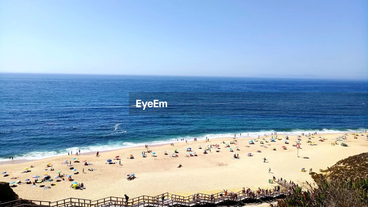 GROUP OF PEOPLE ON BEACH AGAINST SKY