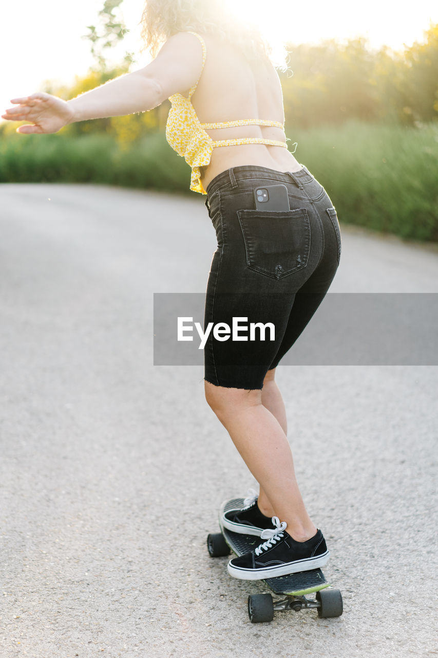 LOW SECTION OF WOMAN ON SKATEBOARD