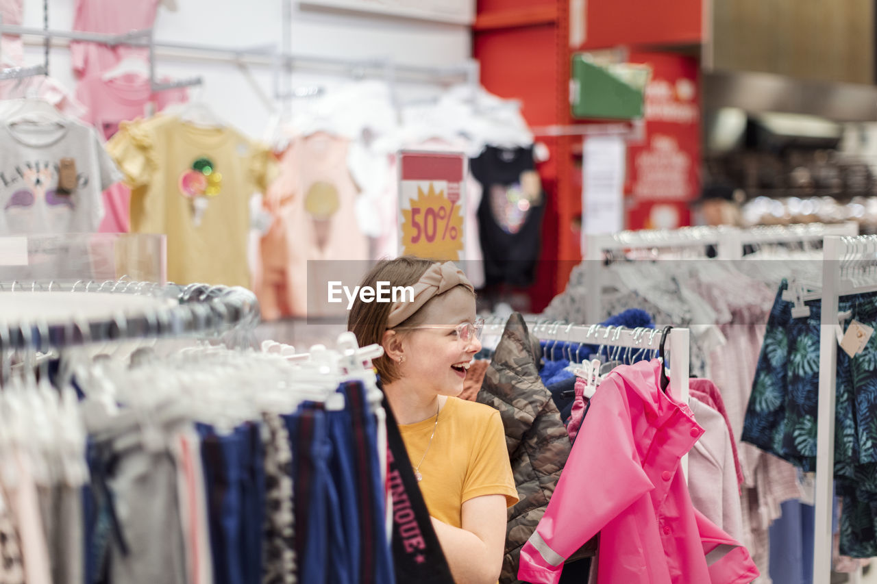 Smiling girl in supermarket looking at clothes