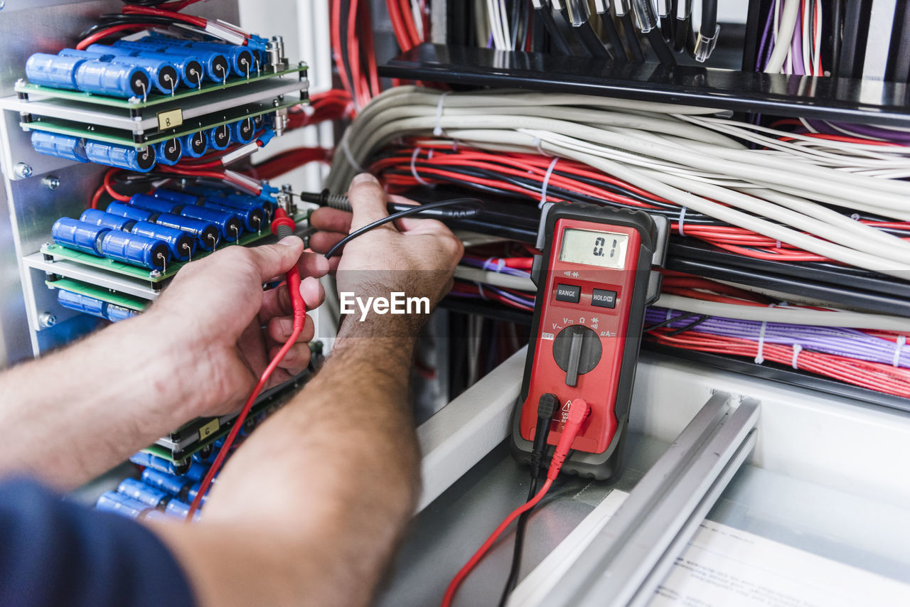 Close-up of man using voltmeter in factory