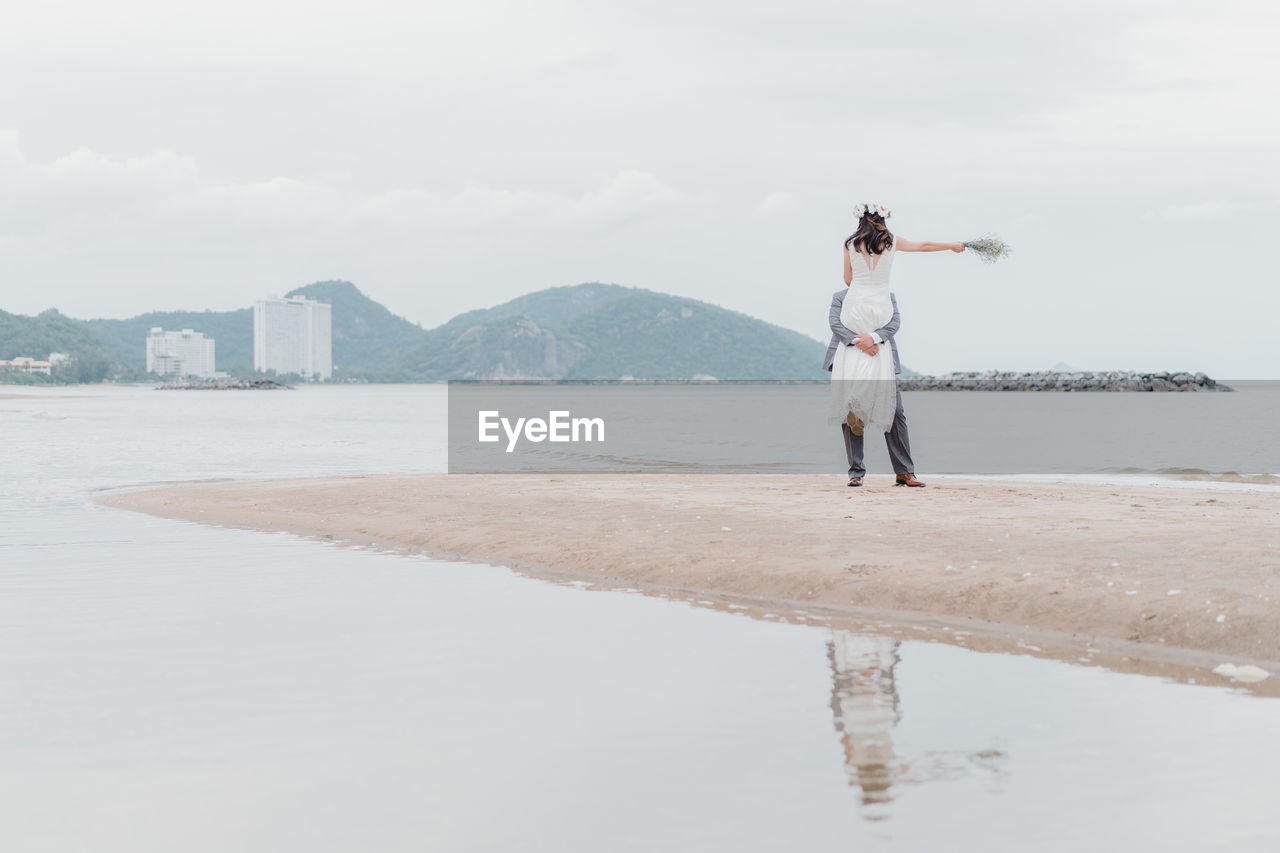 REAR VIEW OF WOMAN STANDING IN WATER