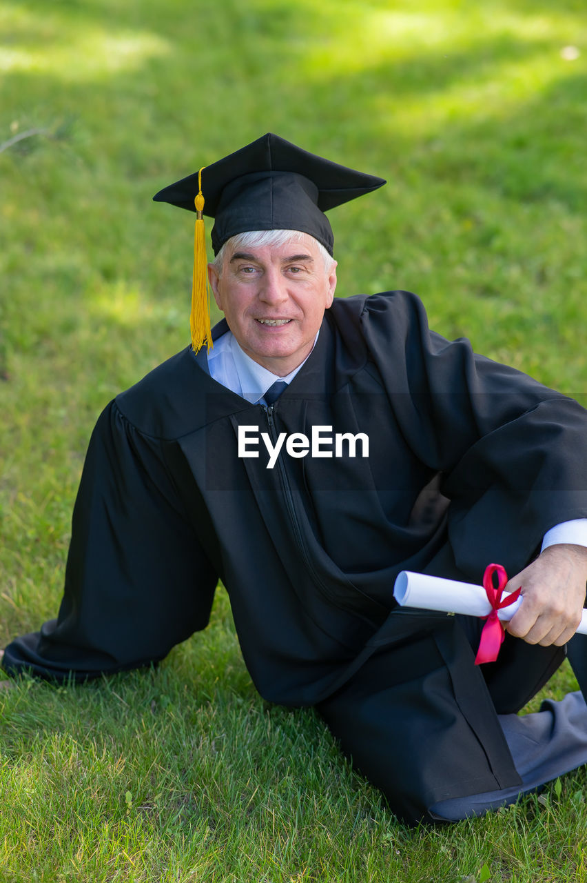 rear view of woman wearing graduation gown standing on field