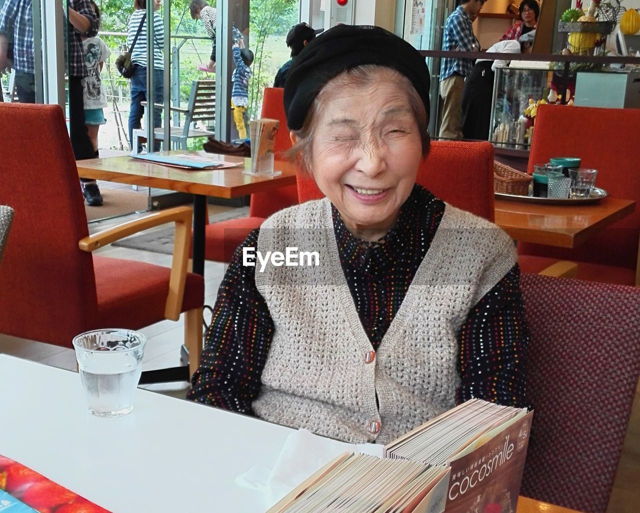 Portrait of smiling senior woman winking eye while sitting in restaurant