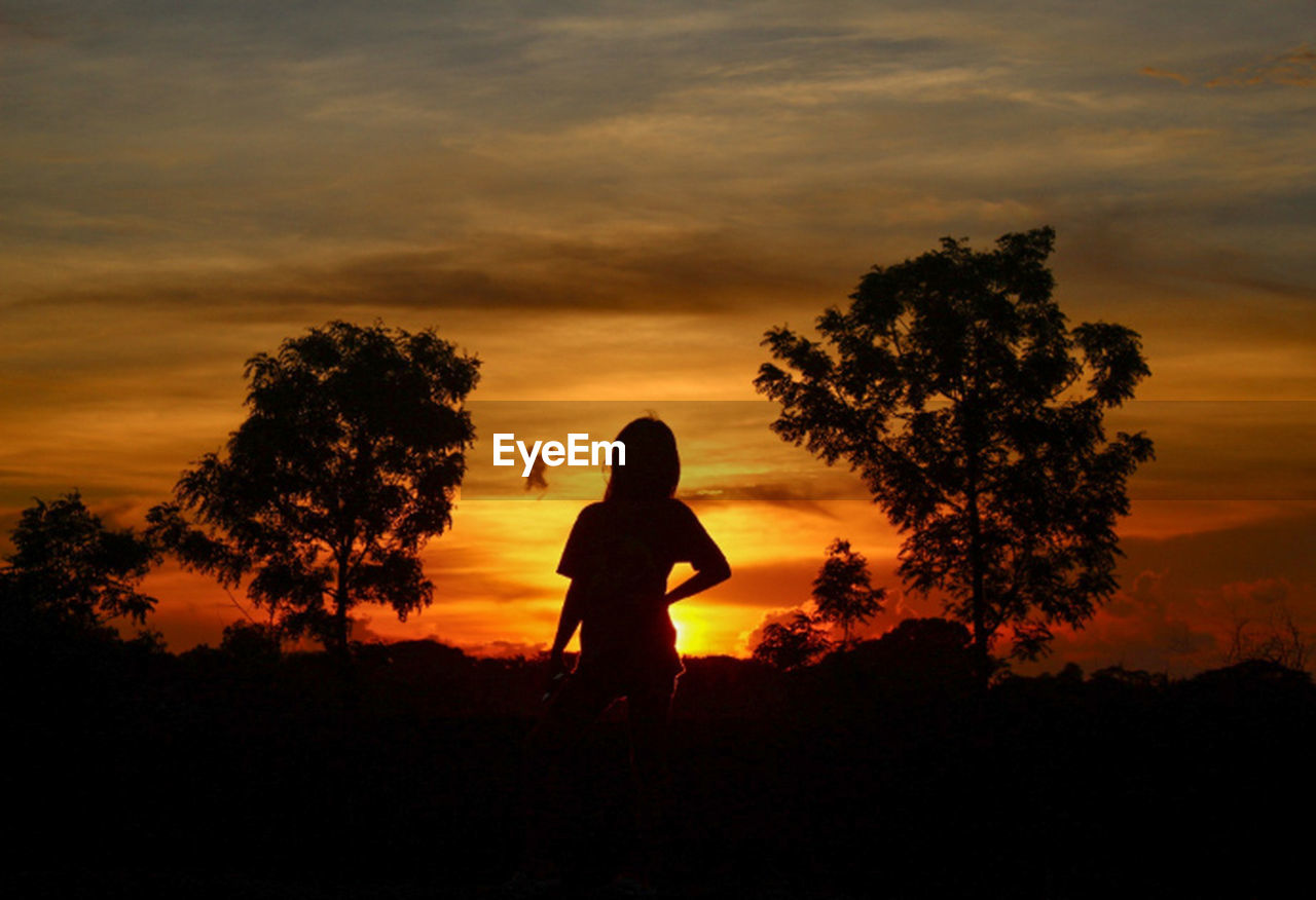 Silhouette woman standing against orange sky