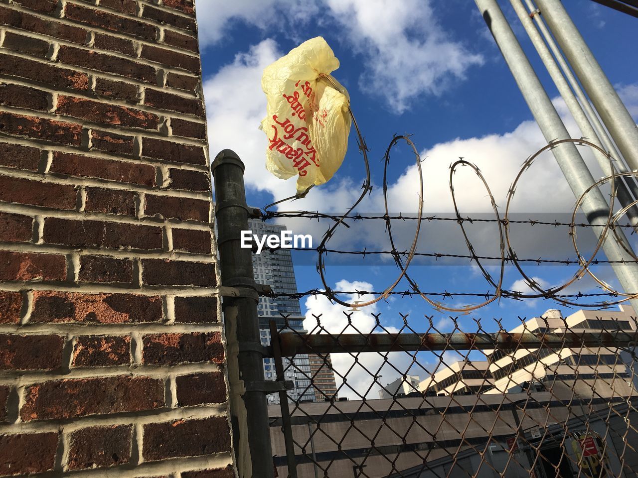 Low angle view of plastic bag stuck on razor wire fence