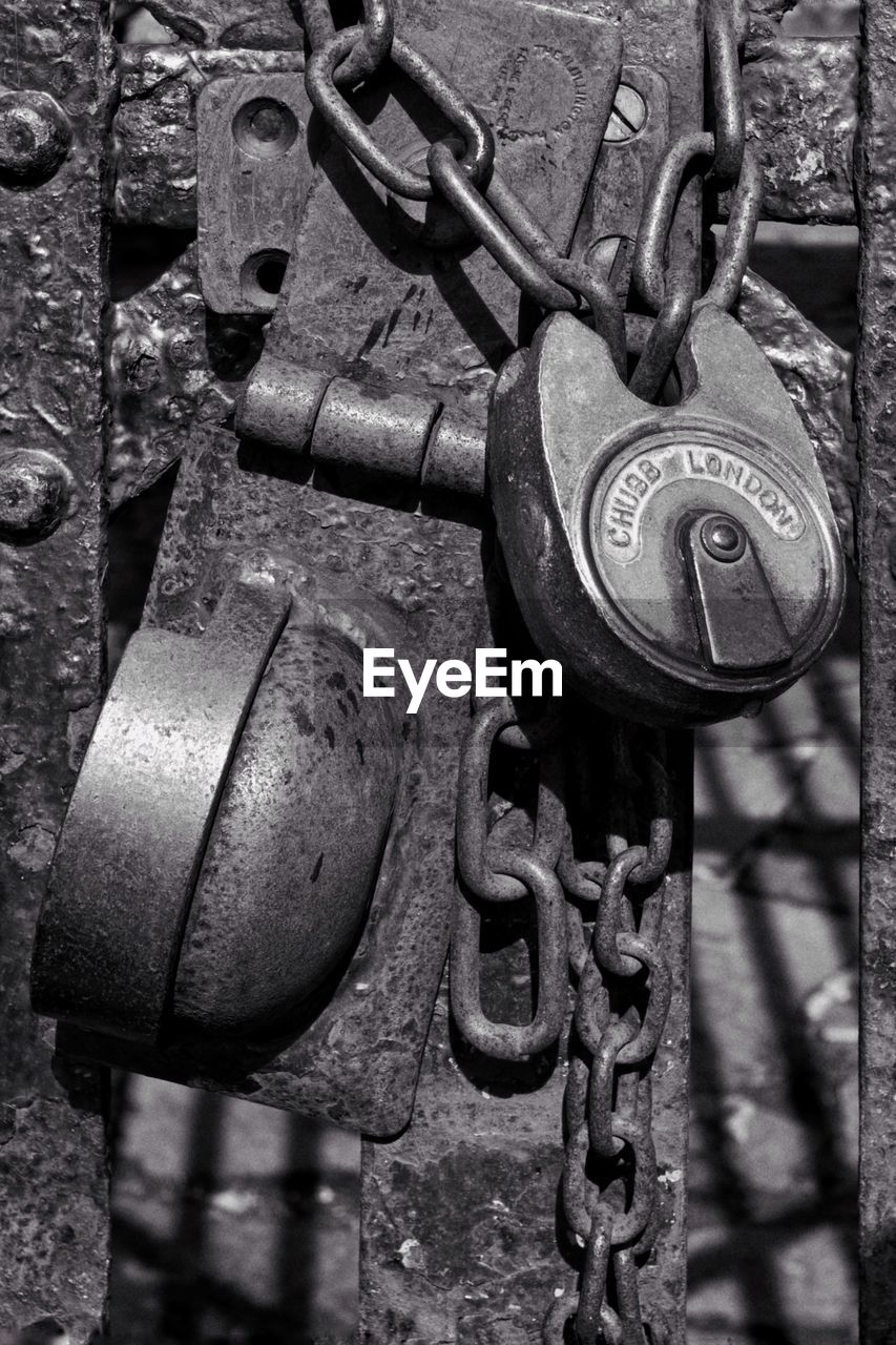 CLOSE-UP OF PADLOCK ON RUSTY METAL CHAIN