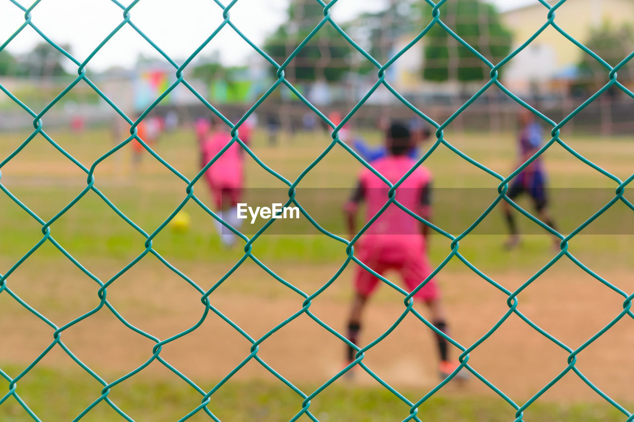 FULL FRAME SHOT OF CHAINLINK FENCE SEEN THROUGH WIRE BEHIND GLASS