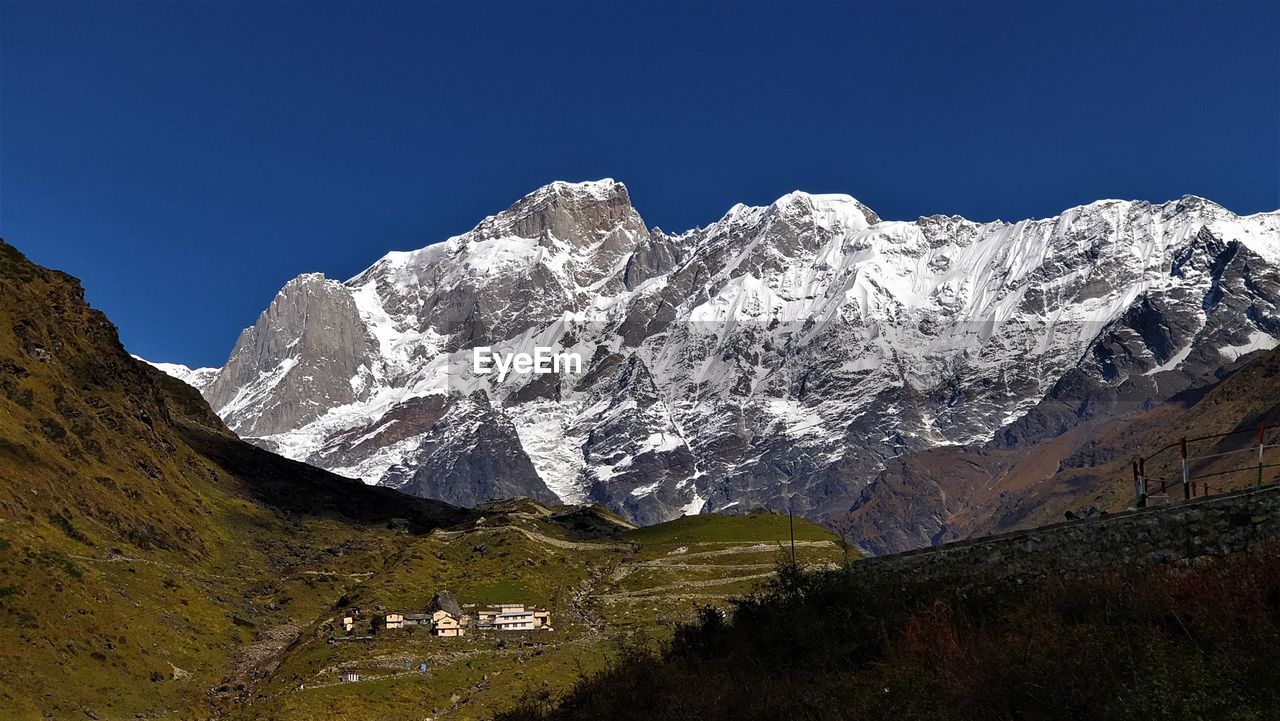 Scenic view of snowcapped mountains against clear blue sky