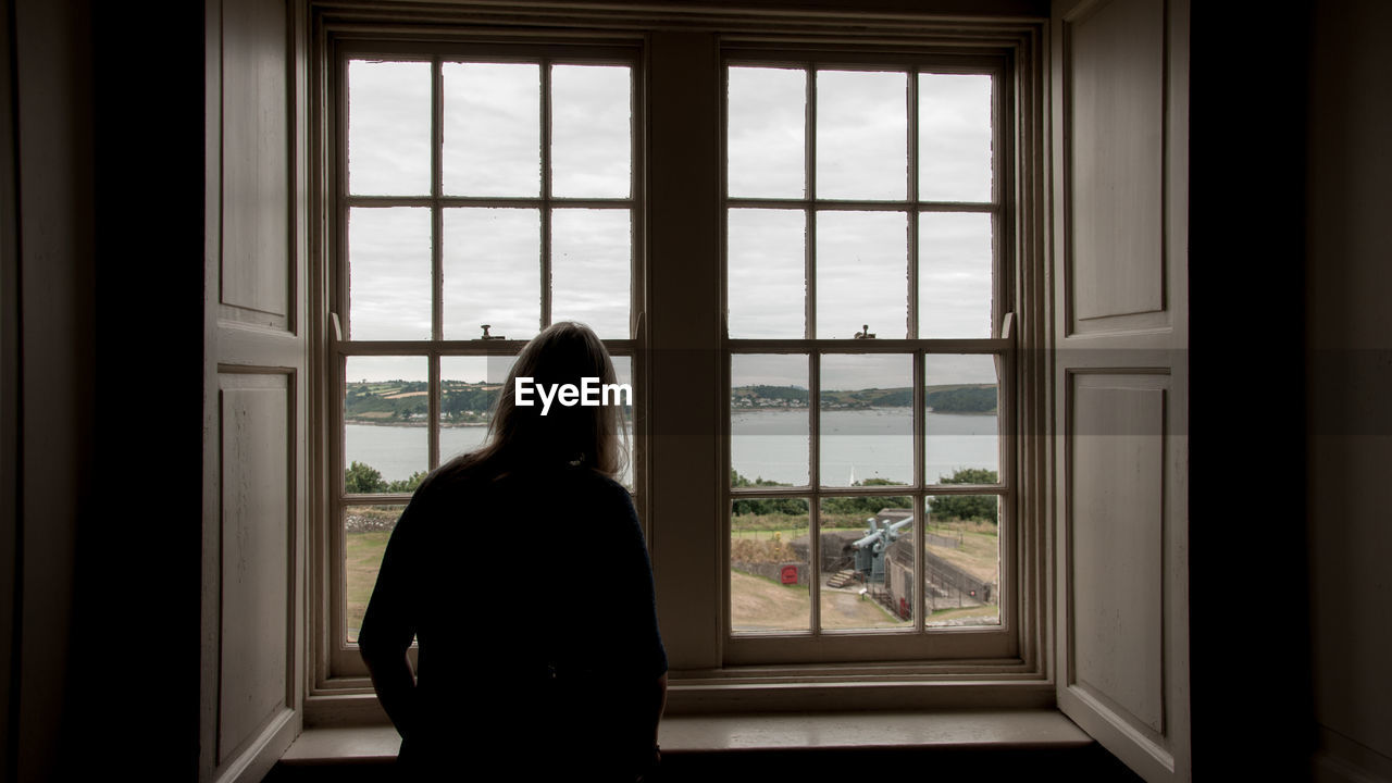 Rear view of woman looking through window