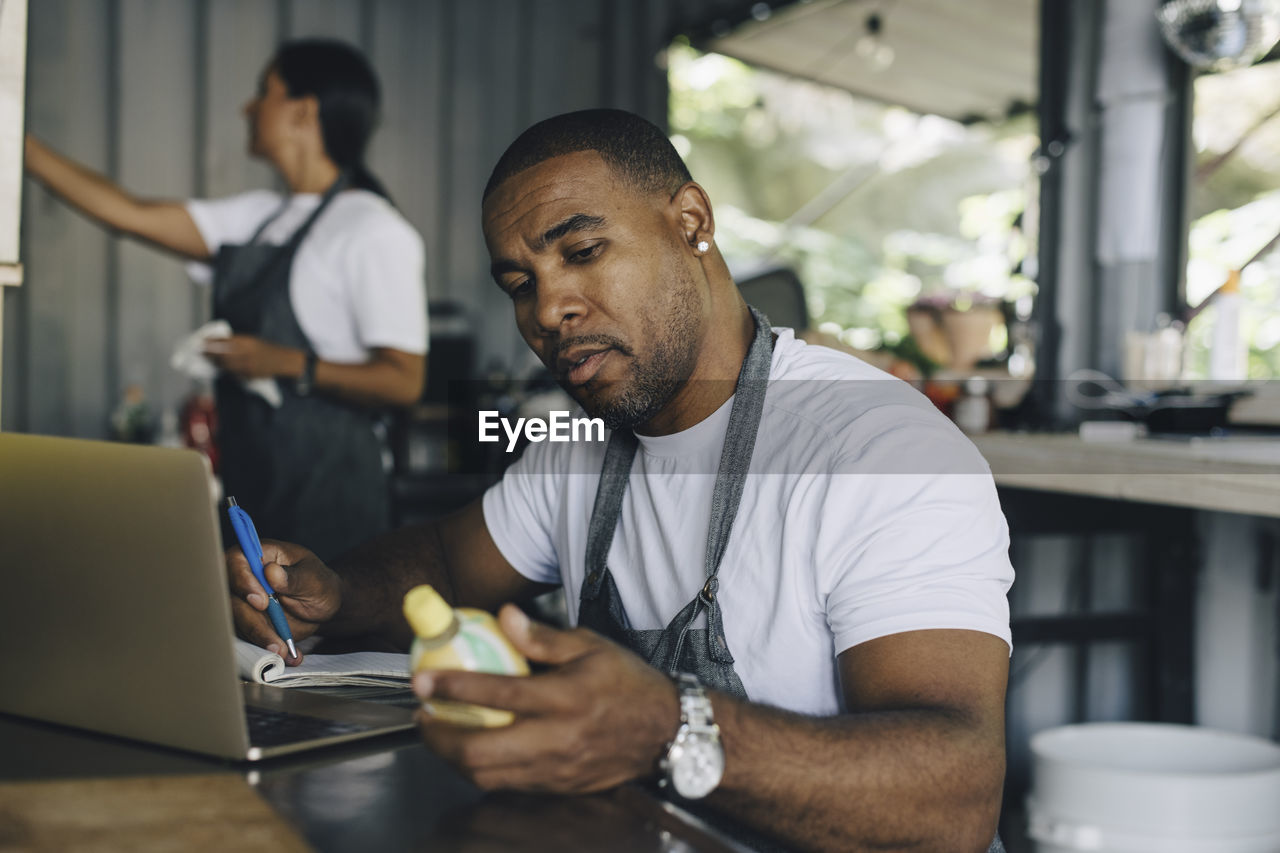 Male seller calculating bill while looking at product in food truck