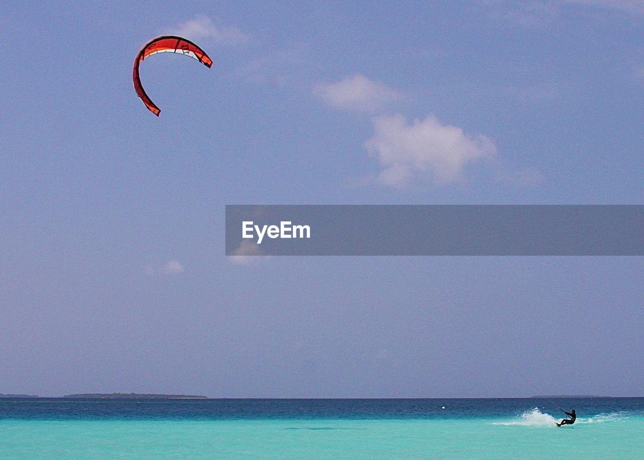 Person kiteboarding in sea against sky