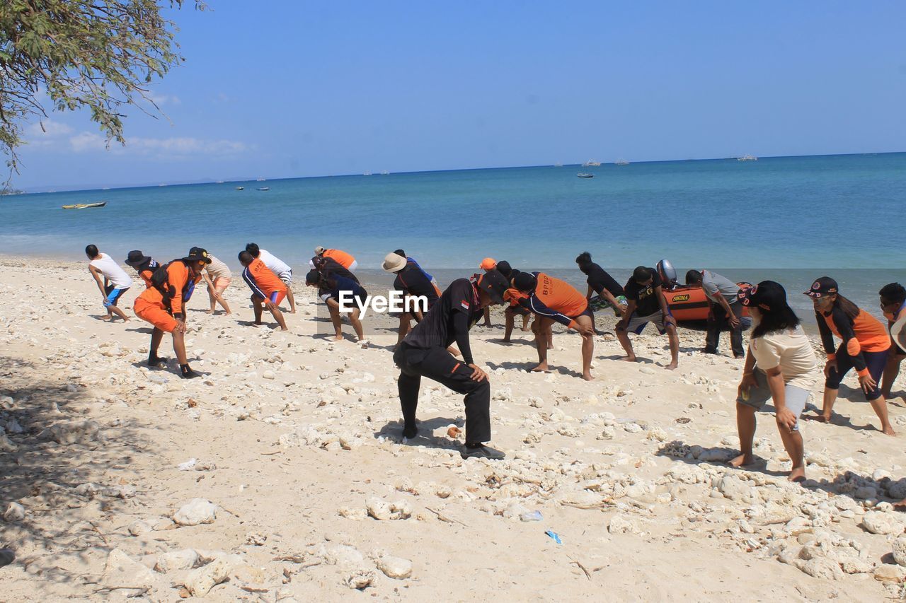 PEOPLE ON BEACH AGAINST CLEAR SKY