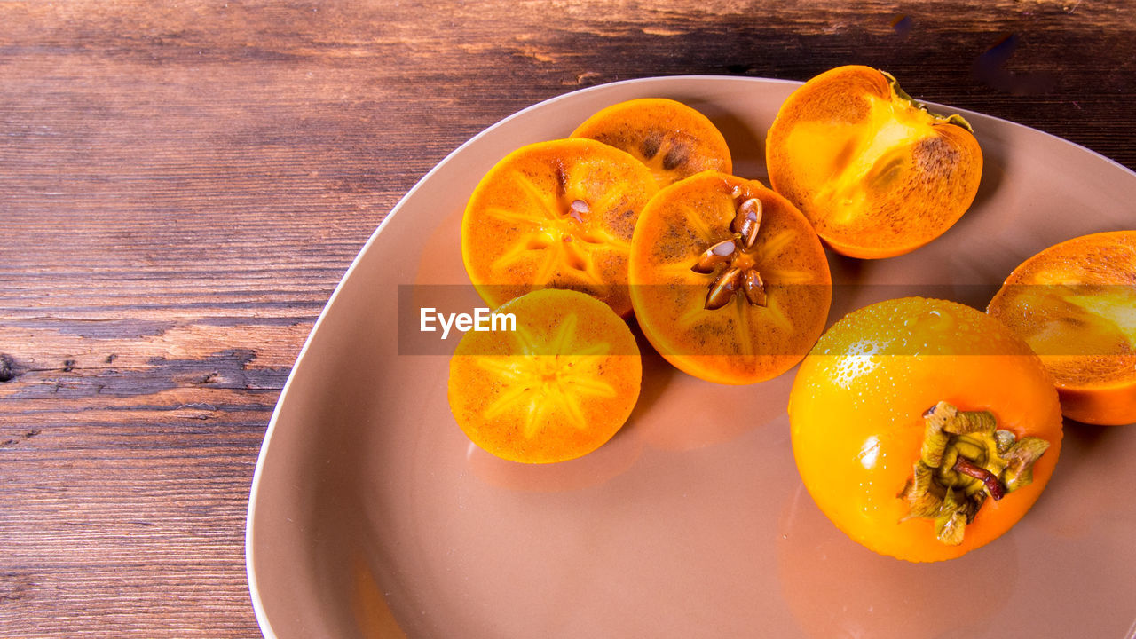 Persimmon cut into halves on a plate on a wooden table,copy space,closeup