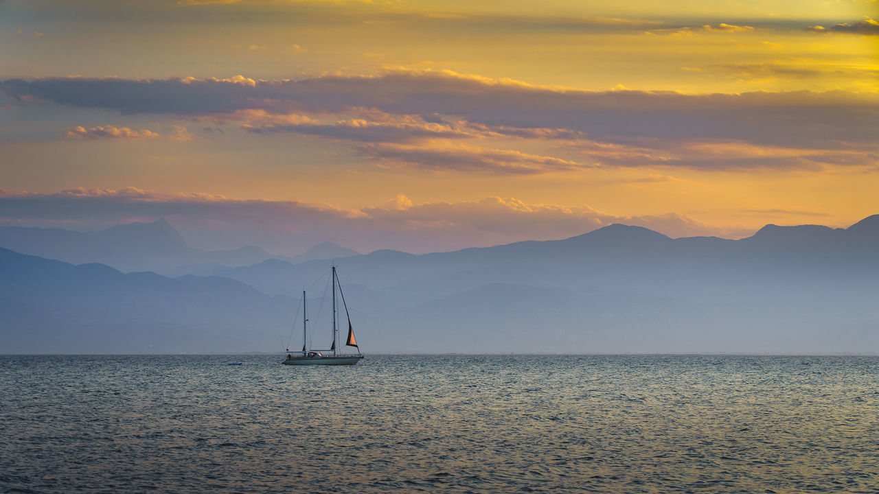 Sailboat sailing on sea against sky during sunset