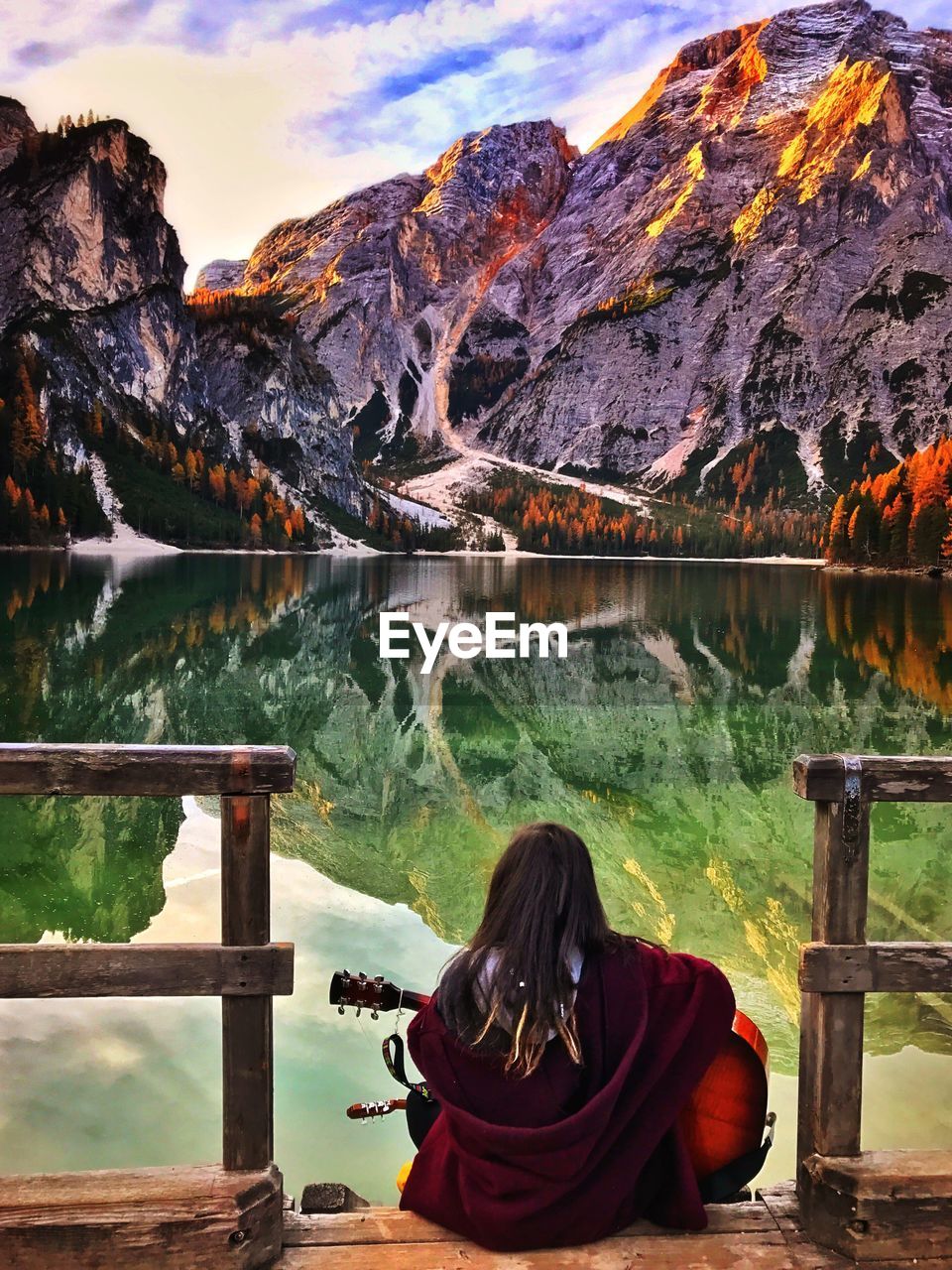 Young woman playing guitar in front of the mountains