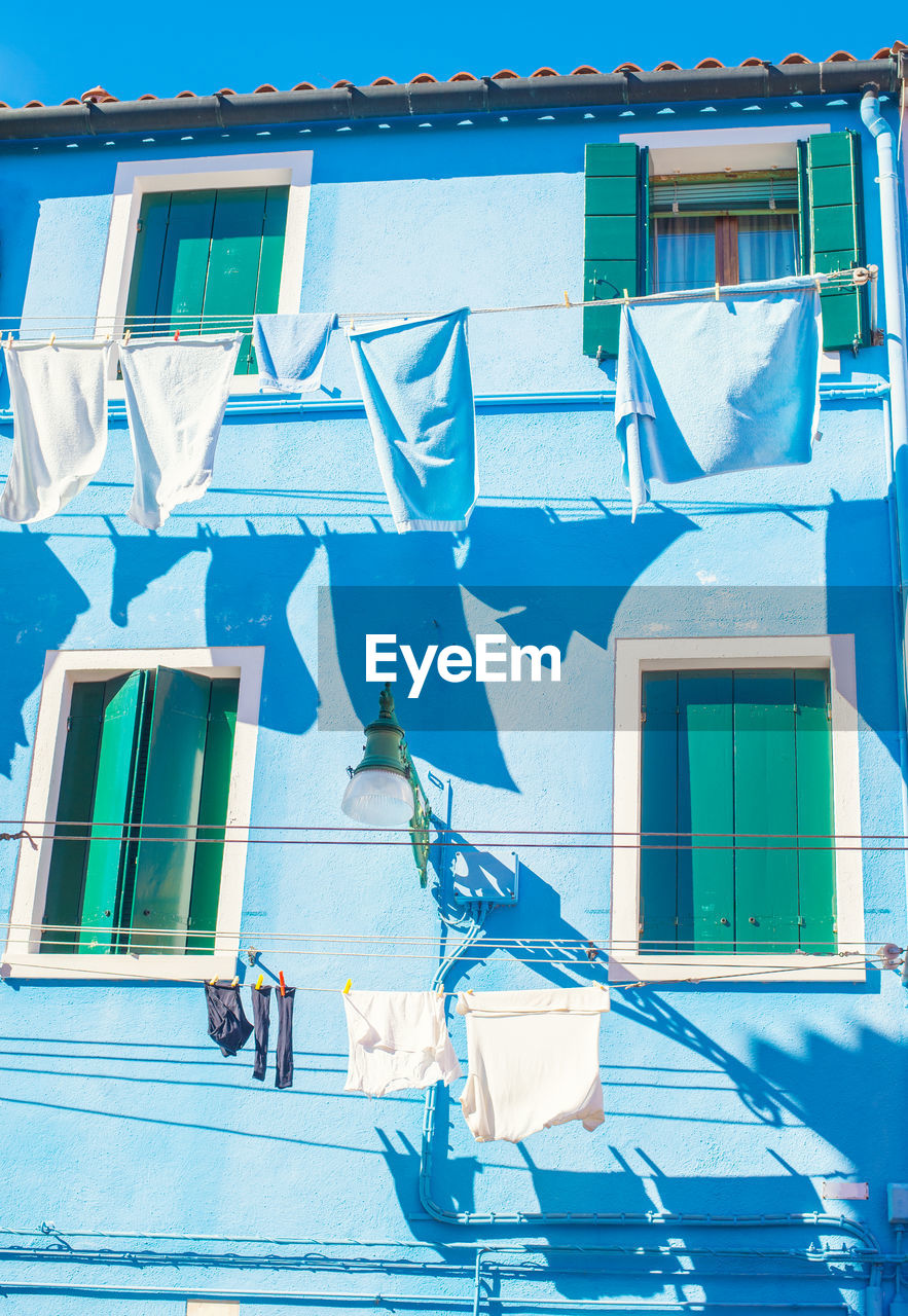 LOW ANGLE VIEW OF CLOTHES DRYING AGAINST BUILDINGS