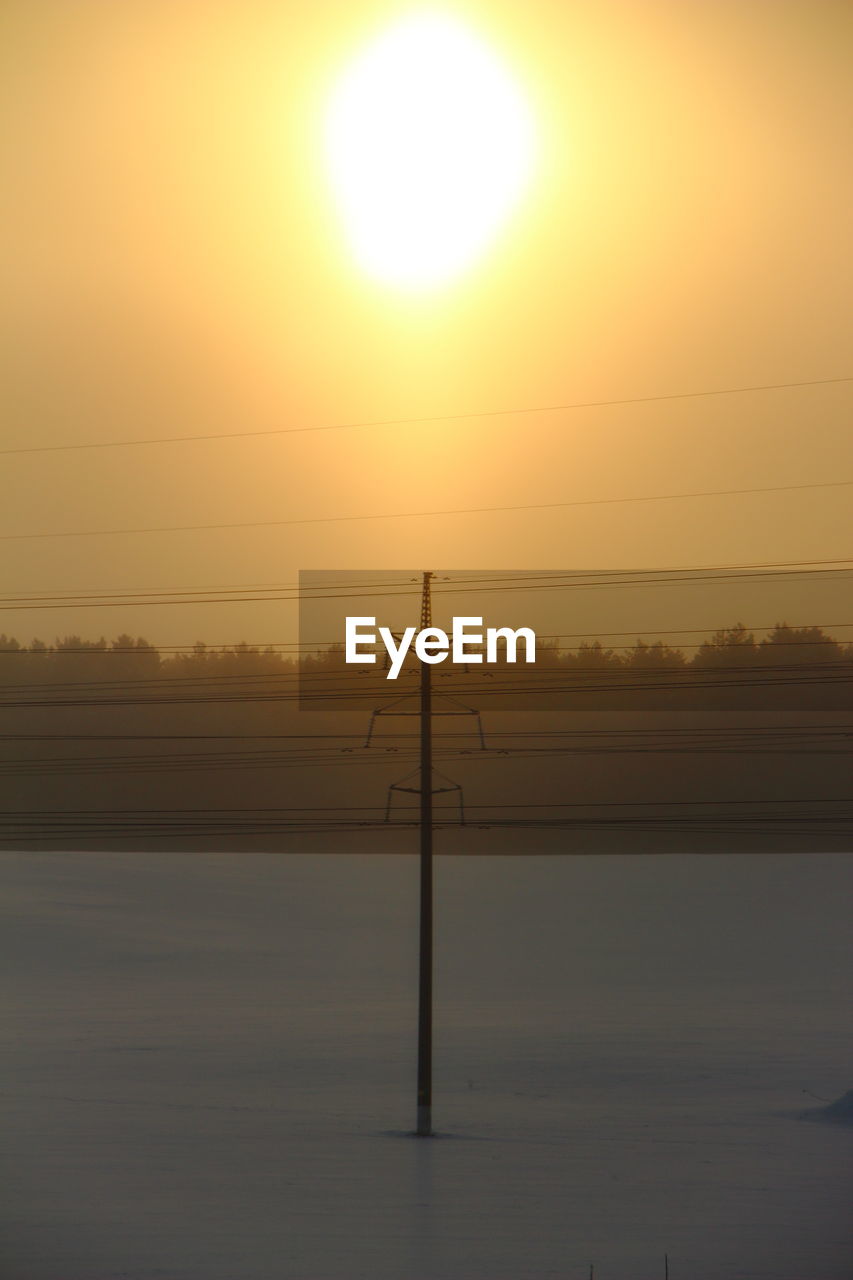 Silhouette electricity pylon against sky during sunset