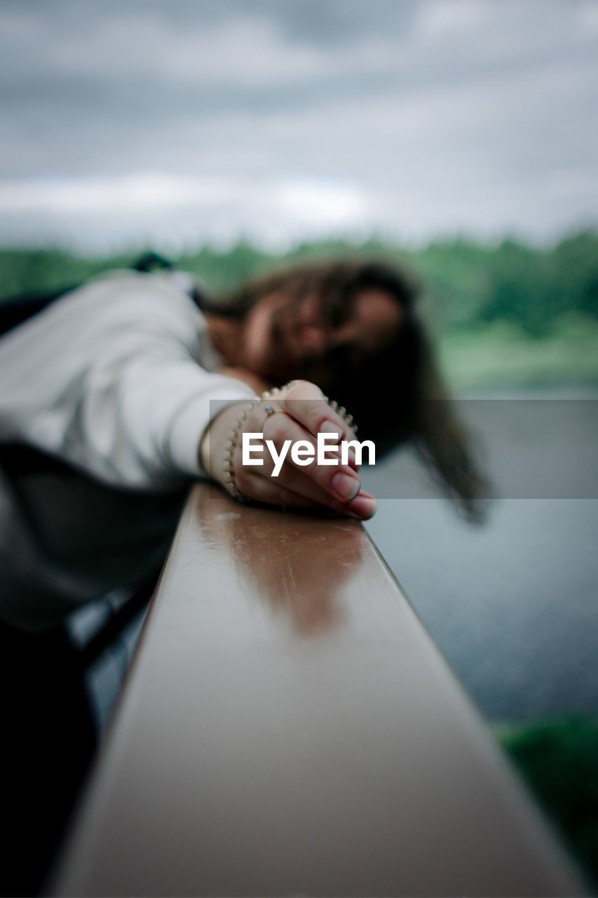 Defocused image of woman relaxing on railing against sky