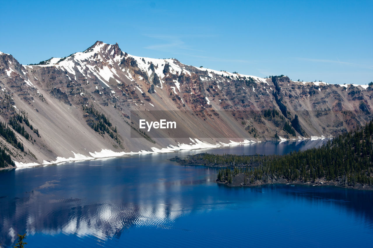 Scenic view of lake and mountains against clear blue sky