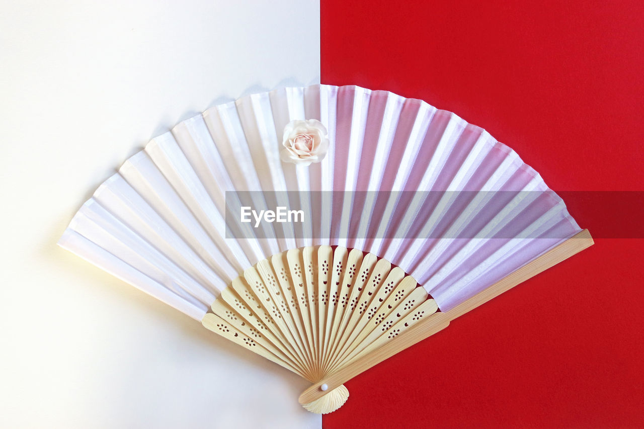 High angle view of hand fan on colored background