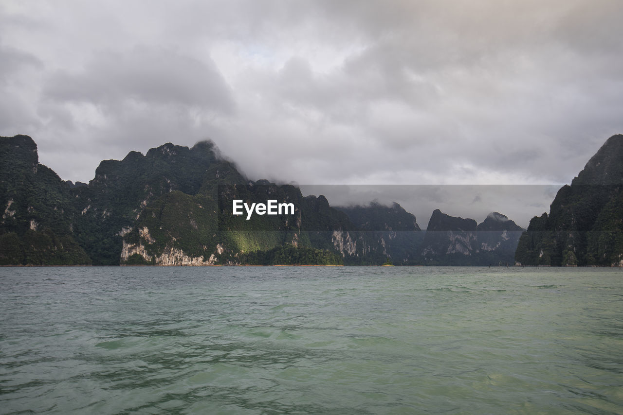 Scenic view of sea and mountains against cloudy sky