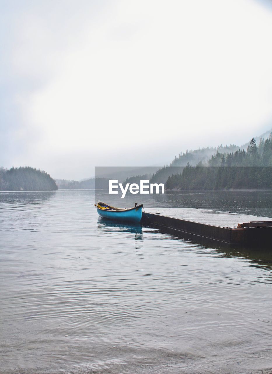 Boat moored at pier on lake against sky