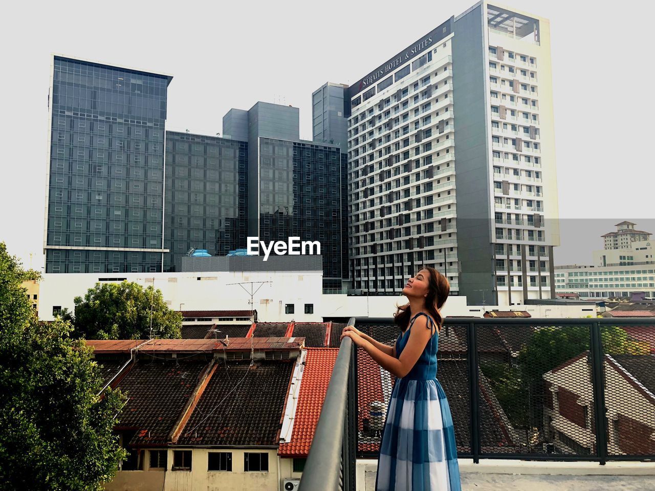 Side view of woman standing against buildings in city