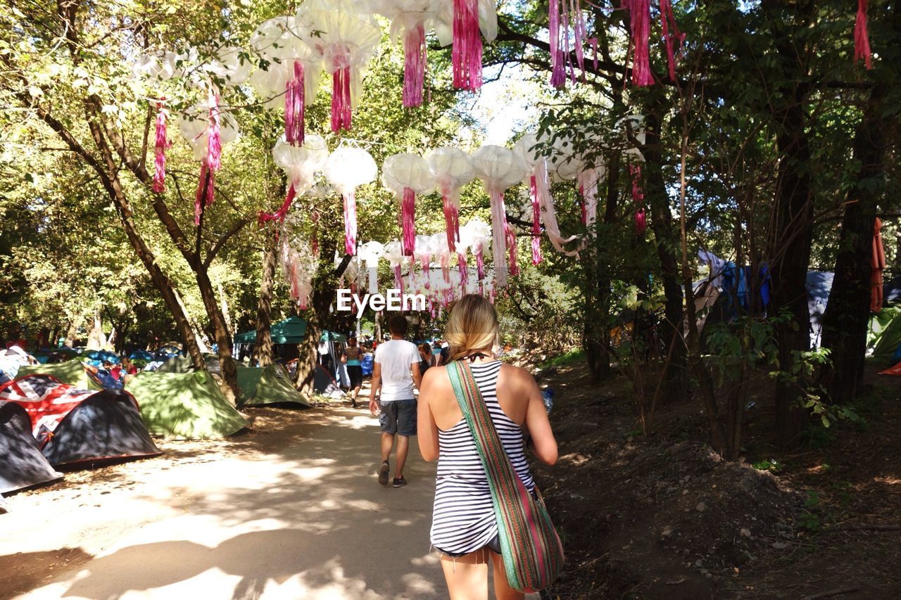 Rear view of man and woman walking on footpath by trees