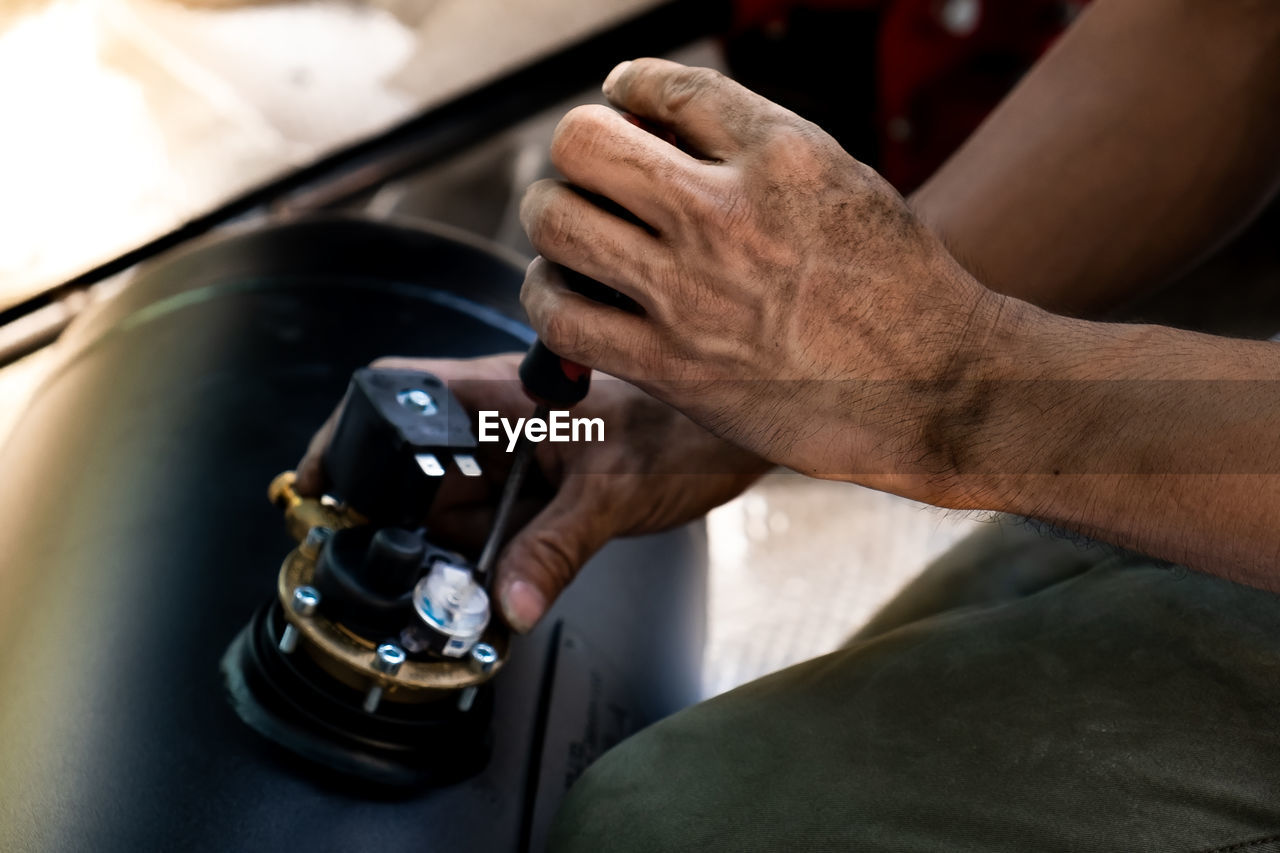 The technician is using a screwdriver to adjust the position of the pressure gauge valve