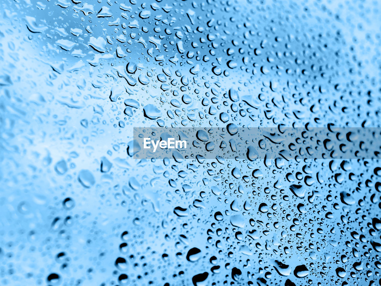 Rain drops on glass. silhouettes of classic blue water drops on a transparent surface.