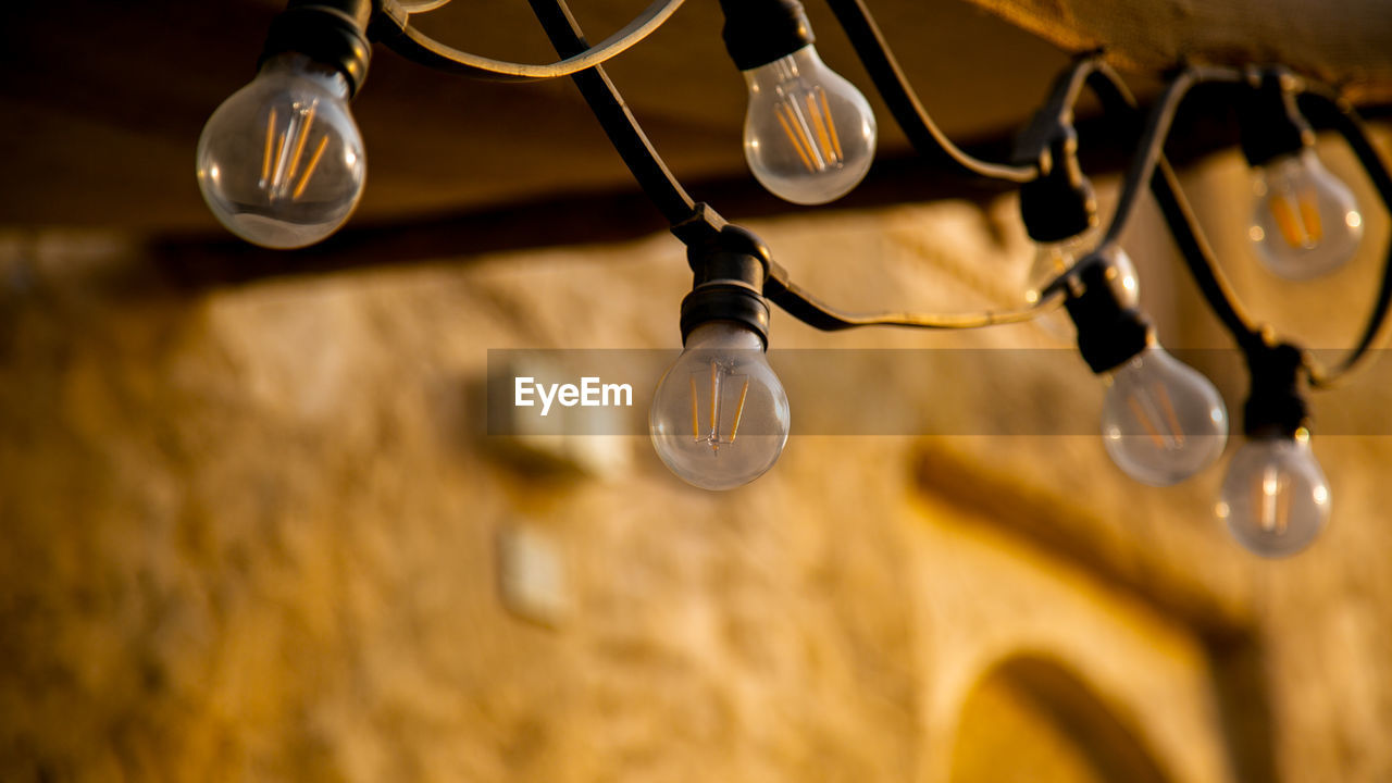 Low angle view of illuminated light bulbs hanging from ceiling