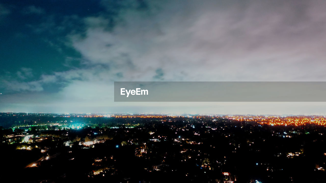 HIGH ANGLE VIEW OF ILLUMINATED CITYSCAPE AGAINST SKY