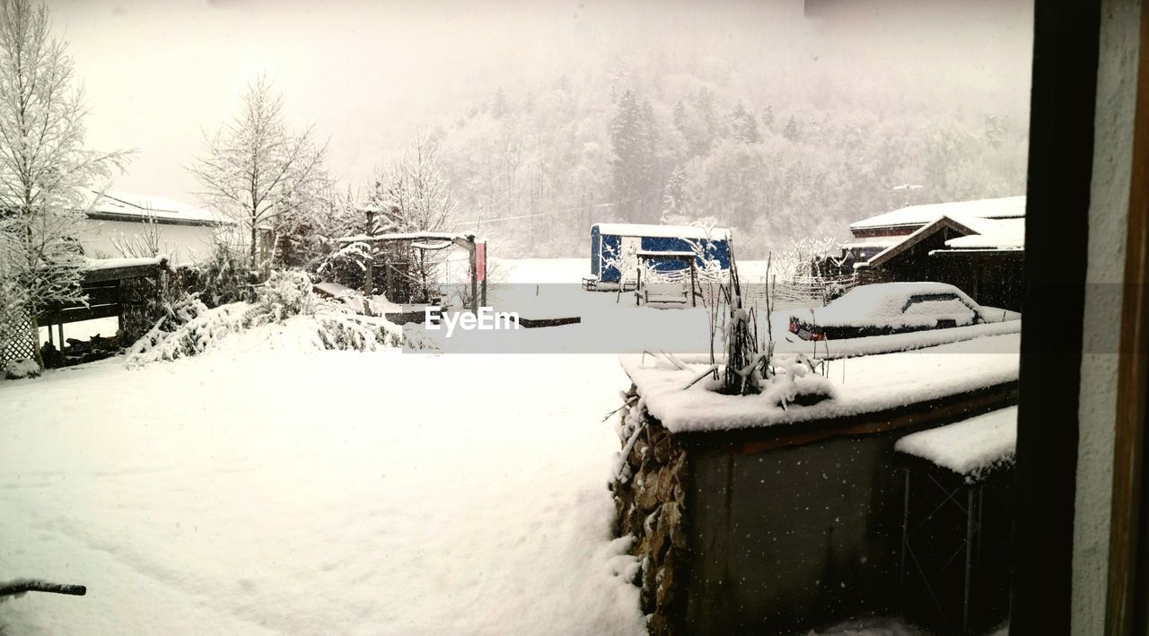 SNOW COVERED HOUSE AGAINST BUILDING