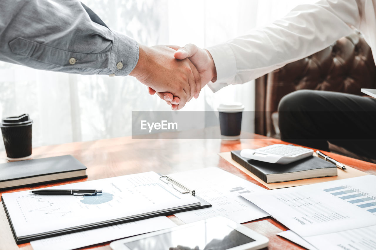 Cropped image of businessmen shaking hands in office