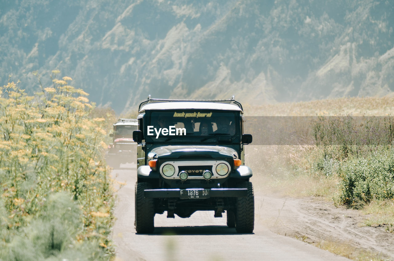 VINTAGE CAR ON ROAD BY LAND