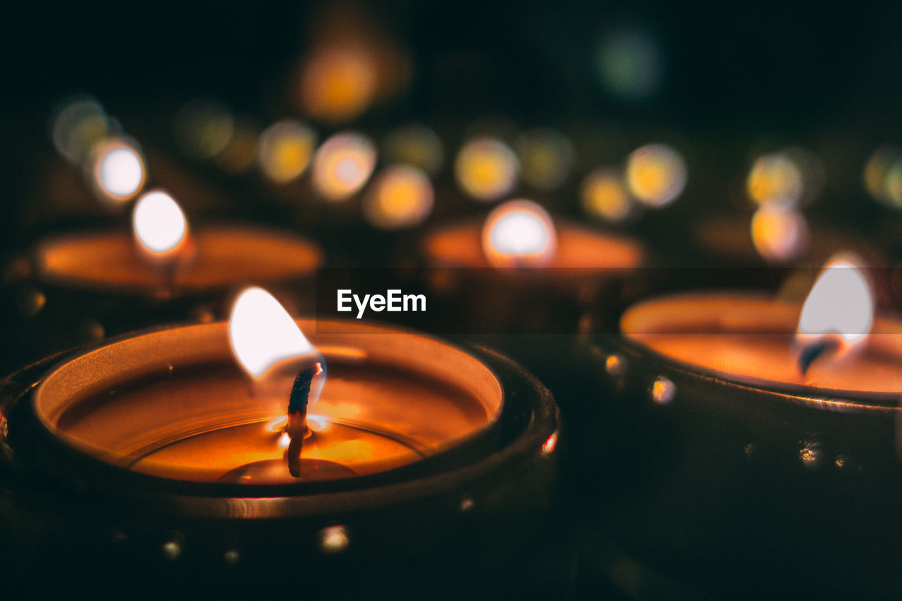 Close-up of illuminated tea lights in darkroom