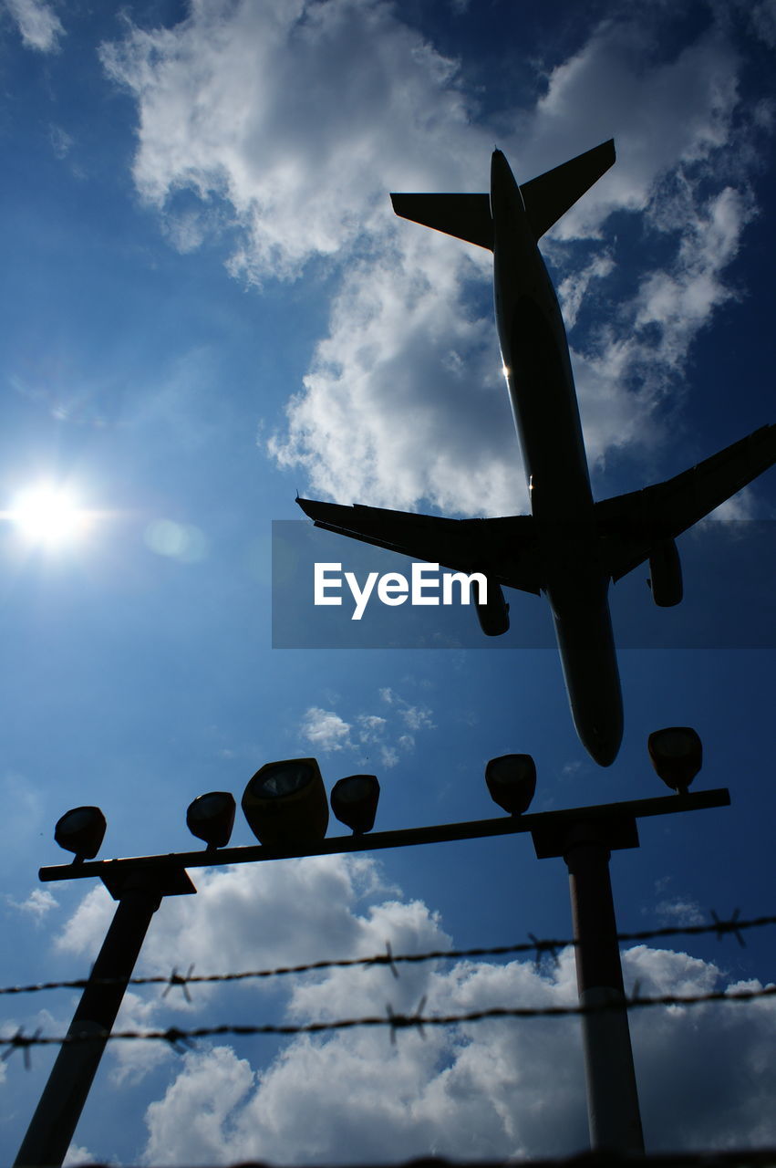 Low angle view of airplane flying over emergency lights against sky