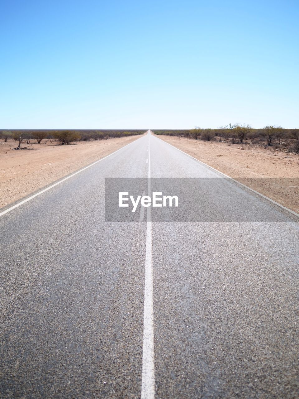 Empty road passing through landscape against clear sky