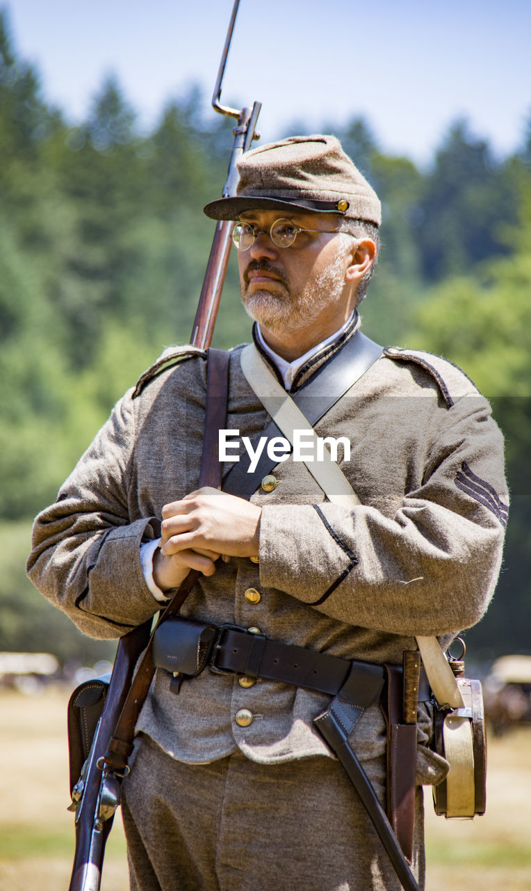 MIDSECTION OF MAN HOLDING CAMERA OUTDOORS