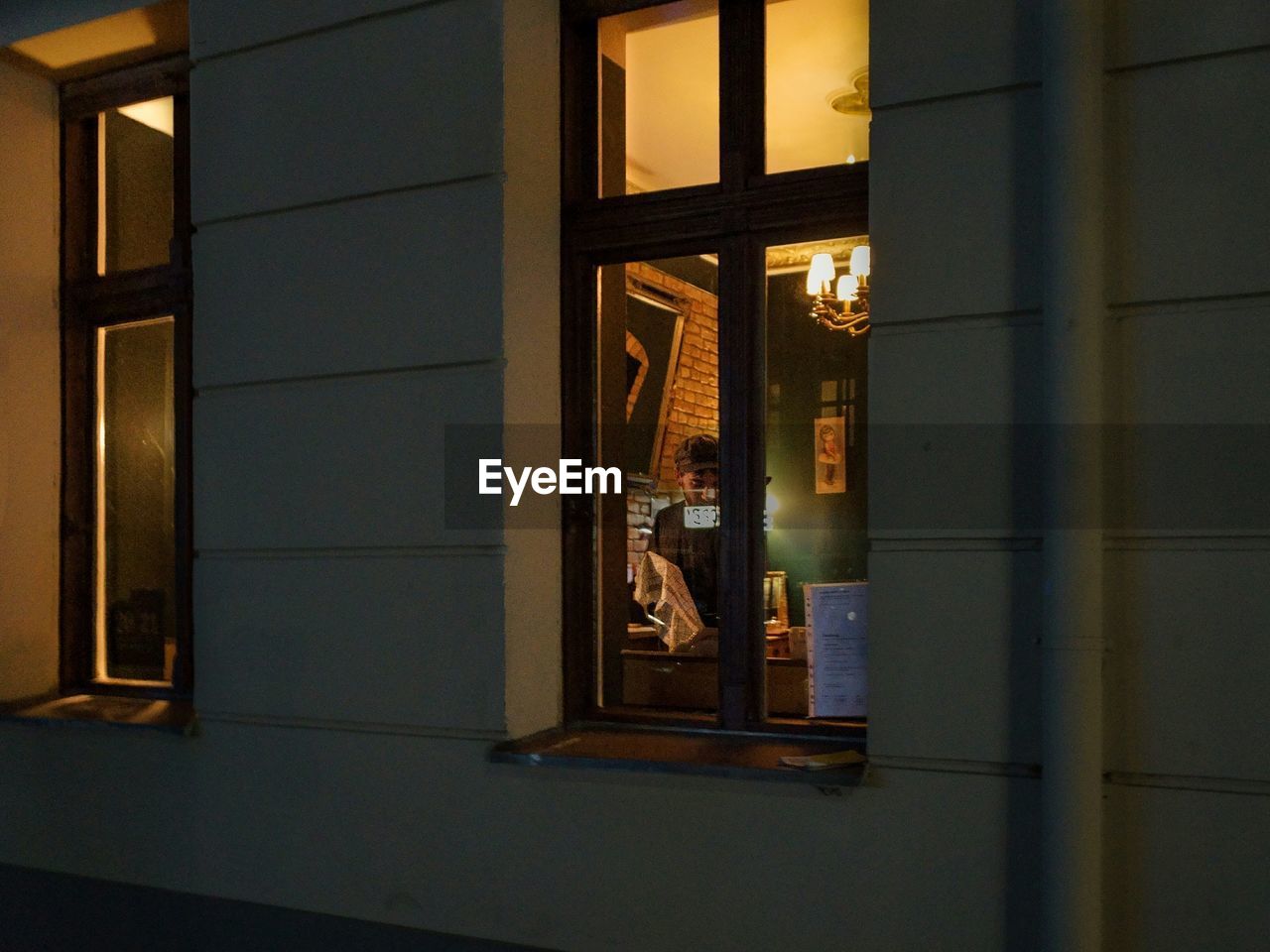 Barkeeper in restaurant seen through window at night