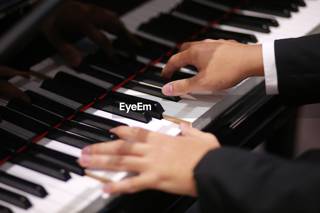 Cropped hands of woman playing piano