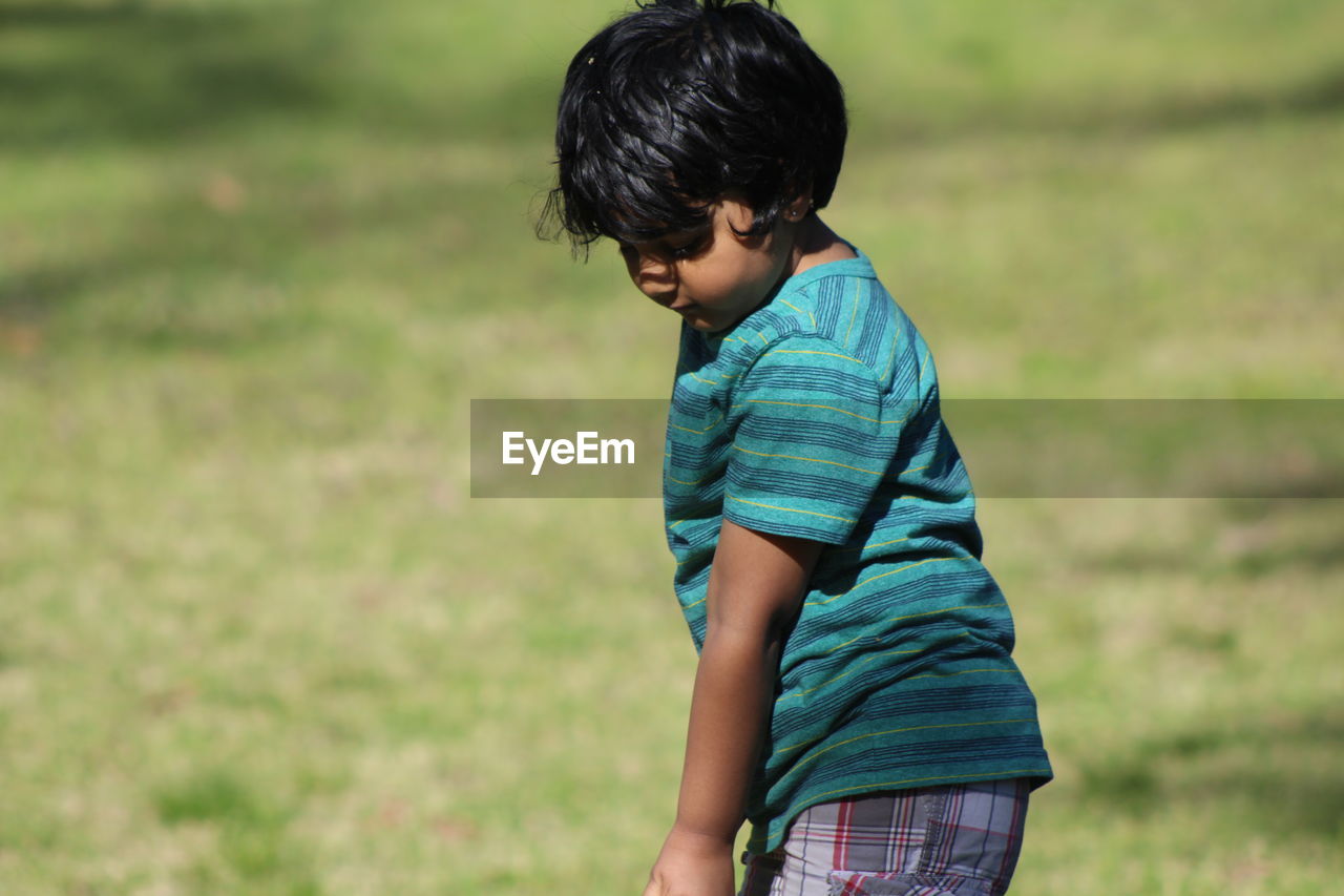 Side view of boy standing on grassy field