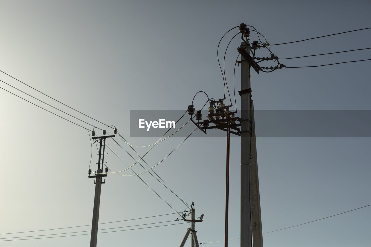 low angle view of electricity pylons against clear sky